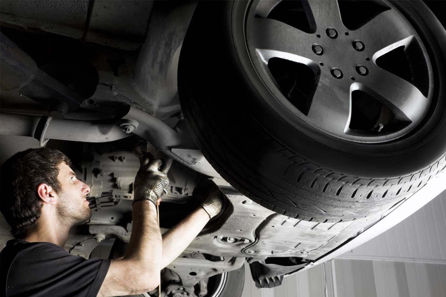 Mechaniker kontrolliert den Unterboden eines Autos